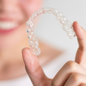 woman-holding-clear-aligner-sq-300